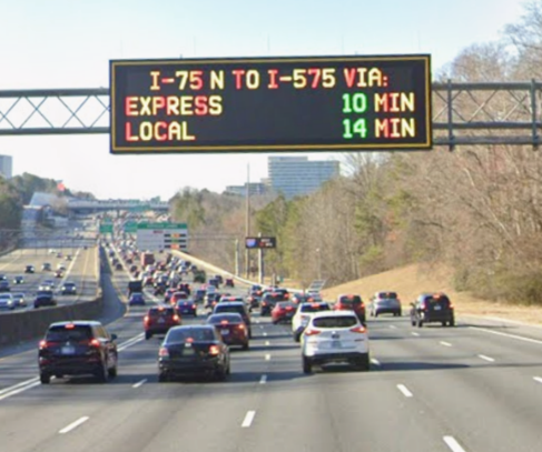 An electronic traffic sign displays a 10-minute travel time for Express lanes compared to 14 minutes for Local lanes.