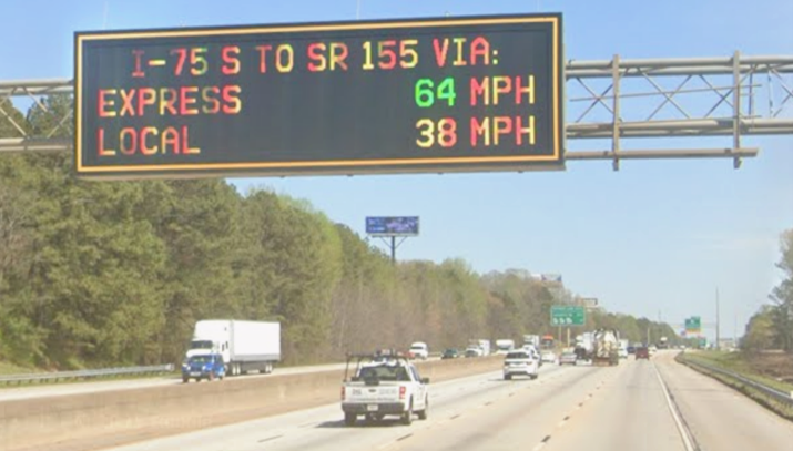 An electronic highway sign shows Express Lanes moving at 65 mph while Local Lanes are at 20 mph.